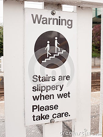 A warning sign saying stairs are slippery when wet please take c Stock Photo