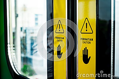 Warning Signs with Hands Symbol on Doors of Indonesia Commuter Train Stock Photo