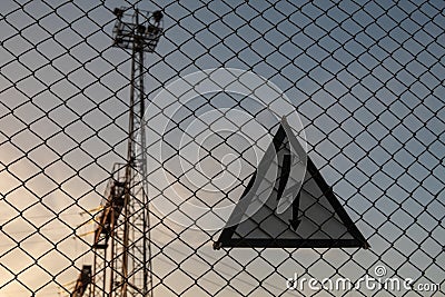 Warning triangular sign with lightning symbol on the fence. Life threatening. High voltage electrical substation Stock Photo