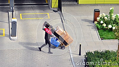 Delivery man pushes hand truck trolley full of cardboards. Editorial Stock Photo
