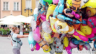 WARSAW, POLAND - JUNE 10, 2017. Female street vendor sells multiple cartoon character helium balloons Editorial Stock Photo