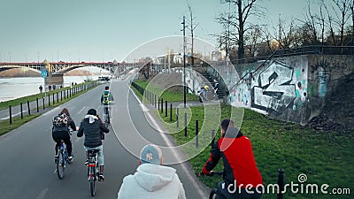 WARSAW, POLAND - MARCH, 27, 2017. Aerial shot of group of young people riding their bikes along evening river embankment Editorial Stock Photo