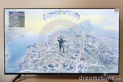 Warzone call of duty 2023 edition battle royal operator flying in a parachute over urzikistan map in an android smart tv Editorial Stock Photo