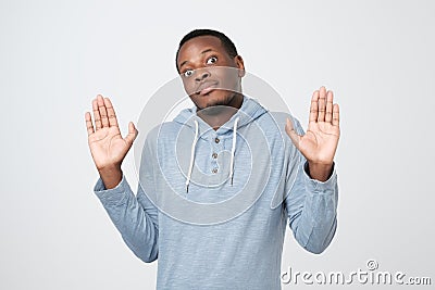 Confused african man raising palms in surrender, shrugging and making clueless expression Stock Photo