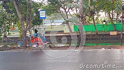 because he was tired, the rickshaw puller rested under the bus stop sign Editorial Stock Photo