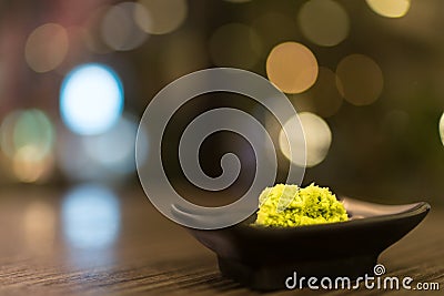 Wasabi in black saucer on wooden table with depth of field effect, Japanese food`s condiment, bokeh background Stock Photo