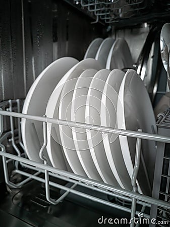 Washed porcelain white plates in the dishwasher. Cleaning and cleanliness concept Stock Photo