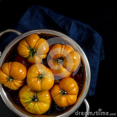 Washed various tomatoes in a colander on a black background Stock Photo