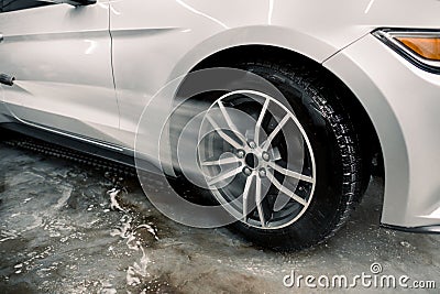 Washing a car by hand, car detailing. Close up image of the process of cleaning the car wheels with a water gun. Car Stock Photo