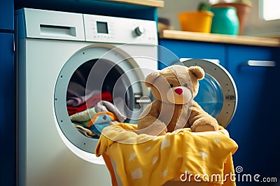 Washing children's clothes. Washing machine with a clean washed towel and a teddy bear in the laundry room Stock Photo