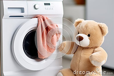 Washing children's clothes. Washing machine with a clean washed towel and a teddy bear in the laundry room Stock Photo