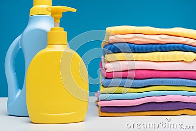 Washing detergents and pile of clean garments on table Stock Photo