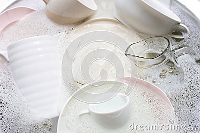 Washing dishes, utensils soaking in kitchen sink Stock Photo