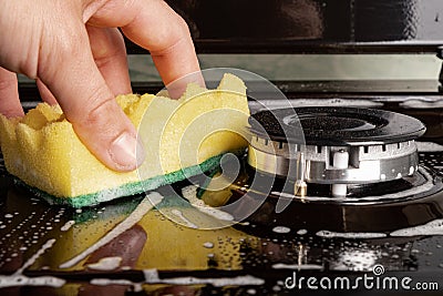 Washing the gas plate with a washcloth and detergent. cleaning the kitchen close upn Stock Photo