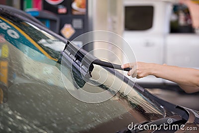 Closeup of a hand washing insects and black-flies from a car windscreen Stock Photo