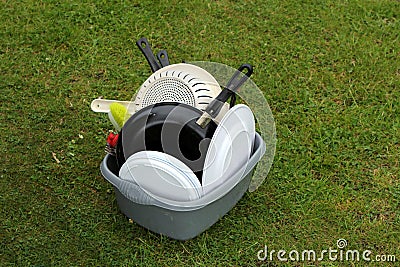 Washing up bowl with dirty pots and plates, on the grass at a ca Stock Photo