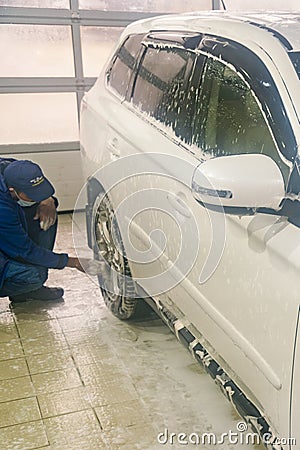 Washing a white car. Man worker washing windshield with sponge on a car wash. Manual car wash in car wash shop service. toned. Editorial Stock Photo