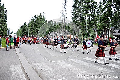 The Prince Albert Highlanders Band and an RCMP and Parks Canada Color Guard march in a parade at Waskesiu to celebrate Canada Day Editorial Stock Photo