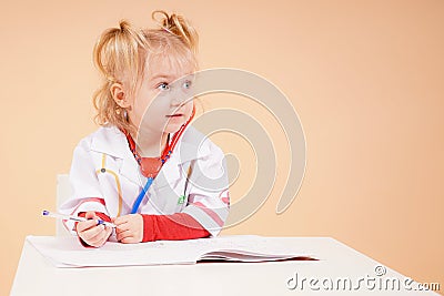 The child doctor sits at the desk and listens to the patient. Stock Photo