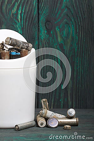 Waste bin. It contains finger-type batteries coated with corrosion. They lie on brushed pine boards painted in black and green Stock Photo