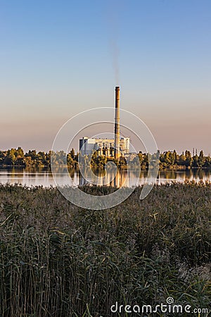 A waste processing plant at the lake sunset, with smoking chimneys. Energy's generated but it results in Stock Photo
