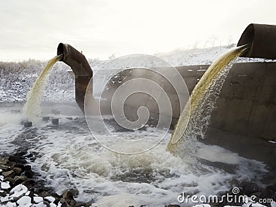 Wastewater from two large rusty pipes merge into the river Stock Photo