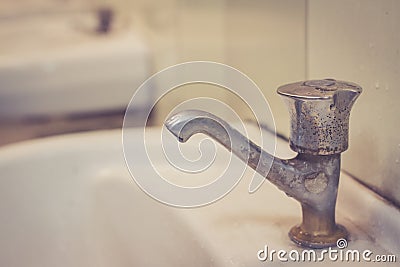 Wasting water, water tap in dirty public toilet. Stock Photo