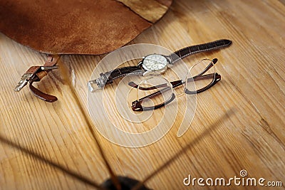 Nice hand watch and brown glasses lying on the wooden table Stock Photo