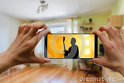 Watching online concert at home by smartphone. Live stream music video Stock Photo