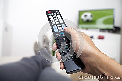 Watching TV. Remote control in hand. Football Stock Photo