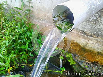 water comes out ofa white paralon pipe with moss on it Stock Photo