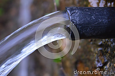 Water flowing through the black pipe Stock Photo