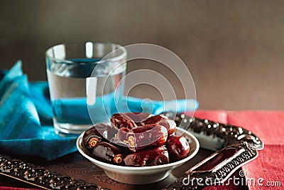 Water and dates on metal tray and blue and red napkins. Traditional Ramadan Iftar food. Stock Photo