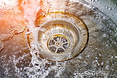 Water drains into the sink, sink and running water for the background, takes care of the water Stock Photo