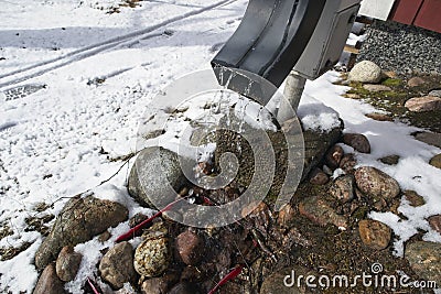 Water dripping from downspout after the snow melts in spring Stock Photo