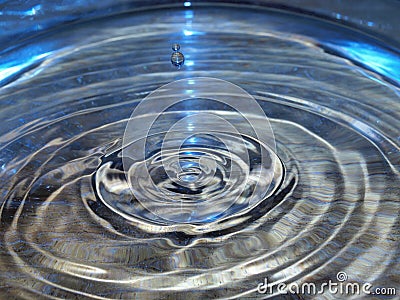 Water droplet in blue lit rippled water Stock Photo