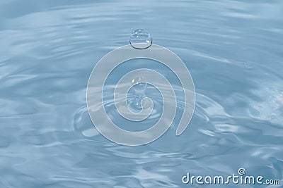 Water droplets falling into clear blue water Stock Photo