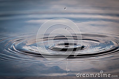 Water Droplets Falling Into A Pond Creating Ripples Stock Photo