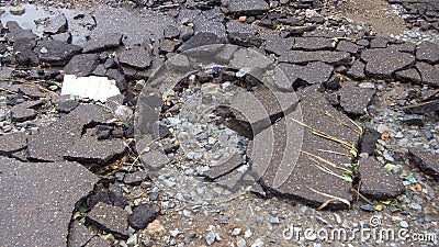 Water erosion of the road. Broken asphalt background. Danger hole, stone gray backdrop Stock Photo