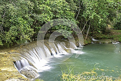 The water flowing over rocks and trees down a waterfall at Kapao waterfall National Park ,Chumphon in Thailand Stock Photo