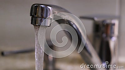 Water flows down from the kitchen faucet. Concept. Clean water flowing from a chrome tap in the kitchen. Stock Photo