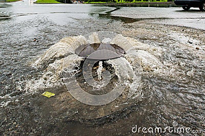 Water flows over the road from the sewer. Stock Photo