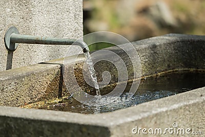 Water flows from a tap at the stone fountain Stock Photo