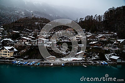 Water Front Wooden Chalets in Interlaken Switzerland on the Aare River with Misty Clouds and Vibrant Blue Water. Editorial Stock Photo