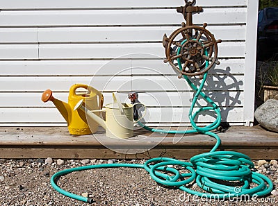 Water hose and watering cans Stock Photo