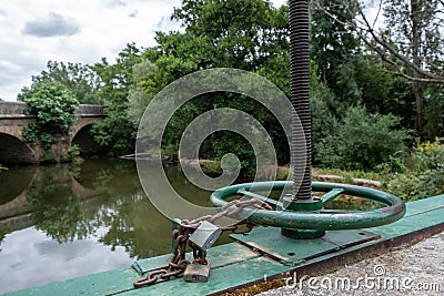 Water lock gate control gears with cogwheels on canal with waterfall Stock Photo