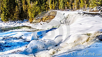 Water of the Murtle River tumbles over the edge of the partly frozen Dawson Falls in the Cariboo Mountains of Wells Gray Stock Photo