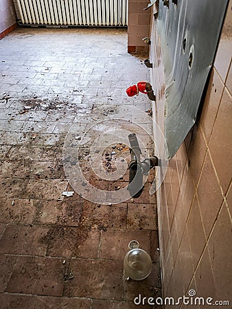 Water pipes out of the wall in destroyed room in old hospital Stock Photo
