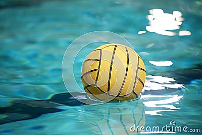 Yellow water polo ball in a swimming pool on blue water background Stock Photo