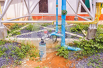 Water pump and piping system at base of local steel water tank t Stock Photo